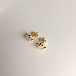 May include: A pair of gold turtle stud earrings with iridescent opal stones.