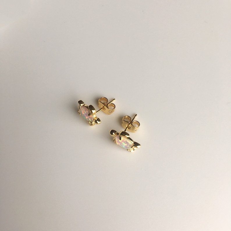 May include: A pair of gold turtle stud earrings with iridescent opal stones.