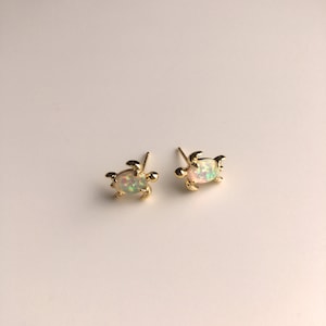 May include: A pair of gold turtle stud earrings with iridescent opal stones.