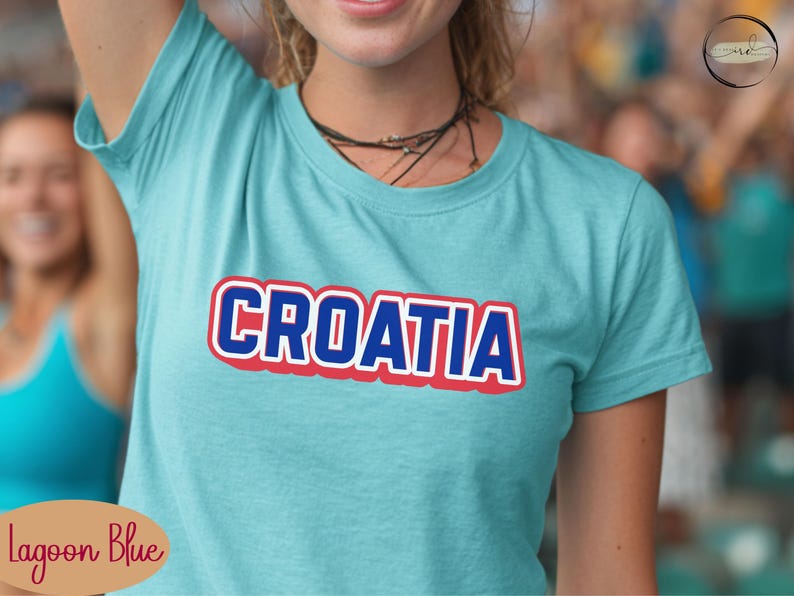 May include: Lagoon blue t-shirt with the word "CROATIA" in bold, white letters with a red outline and a blue shadow. The shirt is short-sleeved and appears to be made of a soft material.