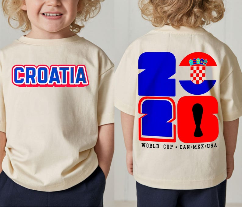 May include: A cream-colored t-shirt with the word "CROATIA" in blue and red lettering on the front. The back of the shirt features the number "2026" in blue and red, with a Croatian flag design and the text "WORLD CUP CAN MEX USA".