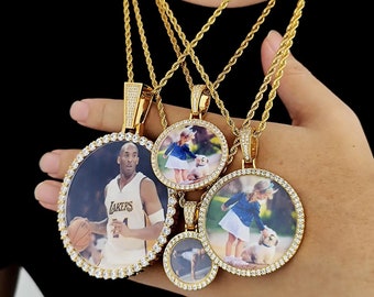 May include: Four gold chains with round photo pendants. The pendants are encrusted with clear cubic zirconia stones. The photos in the pendants include a basketball player, a young girl with a dog, and two other photos.