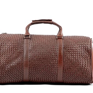 May include: A brown leather woven duffel bag with two top handles and a zippered closure.