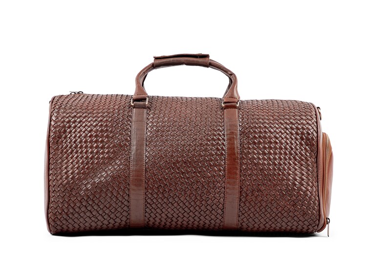 May include: A brown leather woven duffel bag with two top handles and a zippered closure.