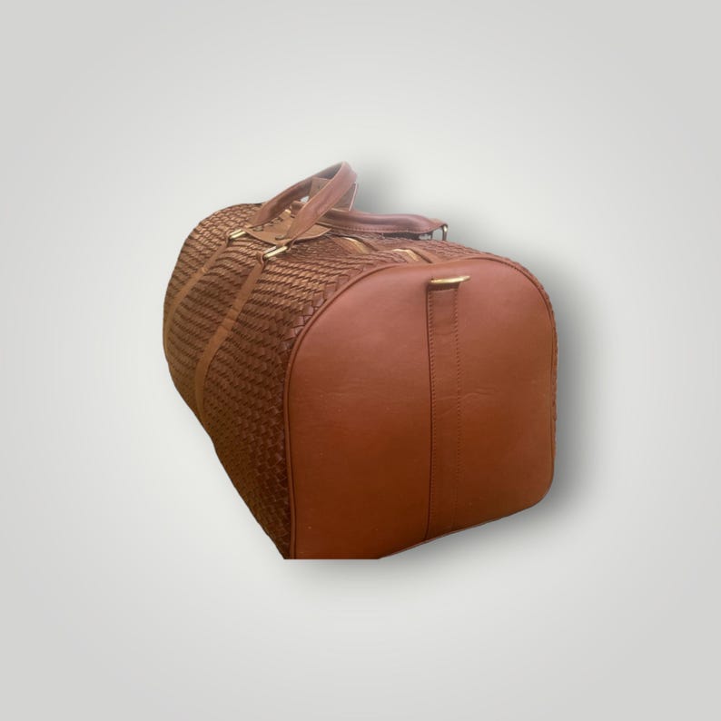 May include: A brown leather duffel bag with a woven pattern. The bag has a top handle and a shoulder strap.