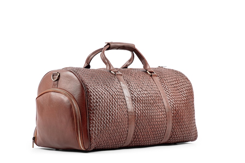 May include: A brown leather duffel bag with a woven pattern and a top handle. The bag has a zipper closure and a side pocket.
