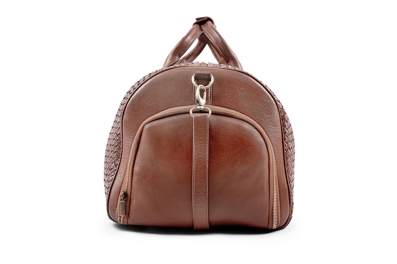 May include: A brown leather duffel bag with a woven pattern and a silver zipper. The bag has a top handle and a shoulder strap.