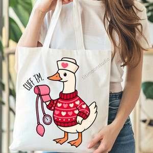 May include: White tote bag featuring a cartoon goose dressed as a nurse, wearing a red sweater with white hearts and a nurse's cap. The goose is holding a blood pressure cuff. Text on the bag reads "CUFF 'EM."