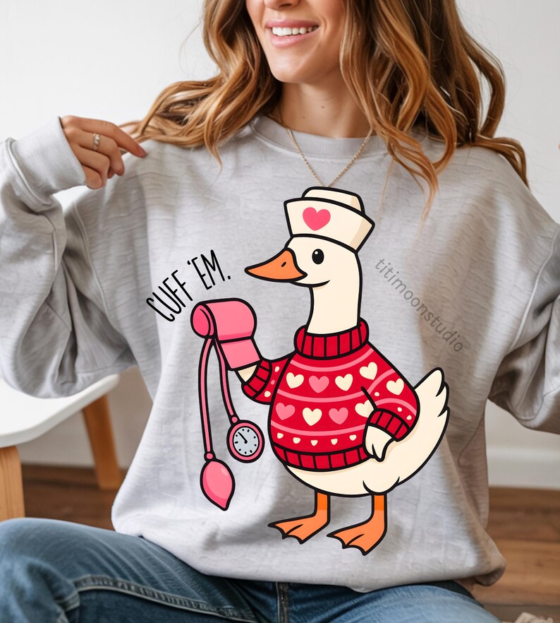 May include: A light gray sweatshirt with a cartoon goose wearing a nurse's hat and a red sweater with white hearts. The goose is holding a pink blood pressure cuff and the text "CUFF 'EM." is printed on the sweatshirt.