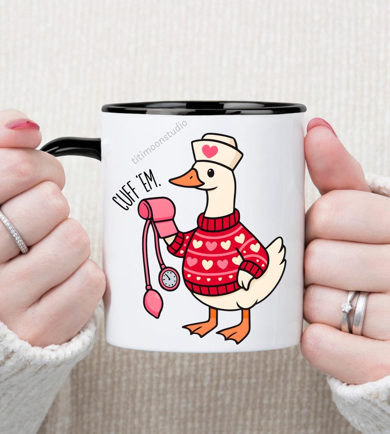May include: White ceramic mug with a black interior and handle. The mug features a cartoon goose wearing a nurse's hat and a red sweater with white hearts. The goose is holding a pink blood pressure cuff. Text on the mug reads "CUFF 'EM."