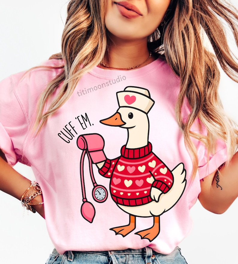 May include: Pink t-shirt with a cartoon goose wearing a nurse's hat and a red sweater with white hearts. The goose is holding a blood pressure cuff and the text "CUFF 'EM" is printed on the shirt.