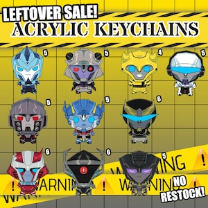 May include: A collection of eleven stylized acrylic keychains featuring various robot characters with distinct color schemes and facial designs. The image includes the text LEFTOVER SALE! ACRYLIC KEYCHAINS, WARNING, and NO RESTOCK! against a yellow grid background.