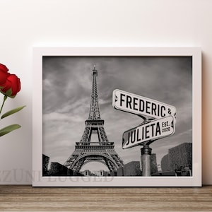 May include: Black and white photo of the Eiffel Tower in Paris, France. Two street signs with the names "FREDERIC & JULIETA Est. 2020" are in the foreground.
