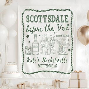 May include: White fabric banner with green text and illustrations. The banner reads "SCOTTSDALE before the Veil" with the date August 25, 2025. Illustrations include a whiskey bottle, cactus, and cowboy boots. The text "Kate's Bachelorette" is also present.