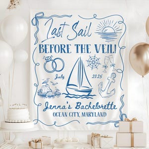 Op de afbeelding: Witte stoffen banner met blauwe nautische illustraties en tekst. De banner luidt "Last Sail Before the Veil!" met afbeeldingen van ringen, een zeilboot en een anker. De tekst "Jenna's Bachelorette" en "Ocean City, Maryland" zijn ook opgenomen.
