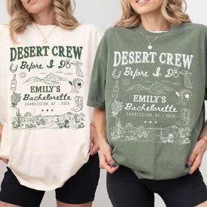 May include: Two t-shirts, one cream and one olive green, with a desert-themed graphic. The design includes text that reads "DESERT CREW Before I Do EMILY'S Bachelorette CHARLESTON, AZ - 2026" along with illustrations of a horseshoe, cactus, and other desert elements.