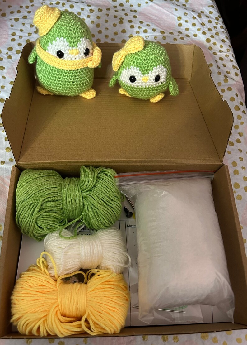 K&ouml;nnte beinhalten: Ein Bastelset zum Herstellen von zwei gr&uuml;nen H&auml;kel-Pinguin-Pl&uuml;schtieren. Das Set enth&auml;lt gr&uuml;nes, wei&szlig;es und gelbes Garn, F&uuml;llmaterial und eine H&auml;kelnadel.