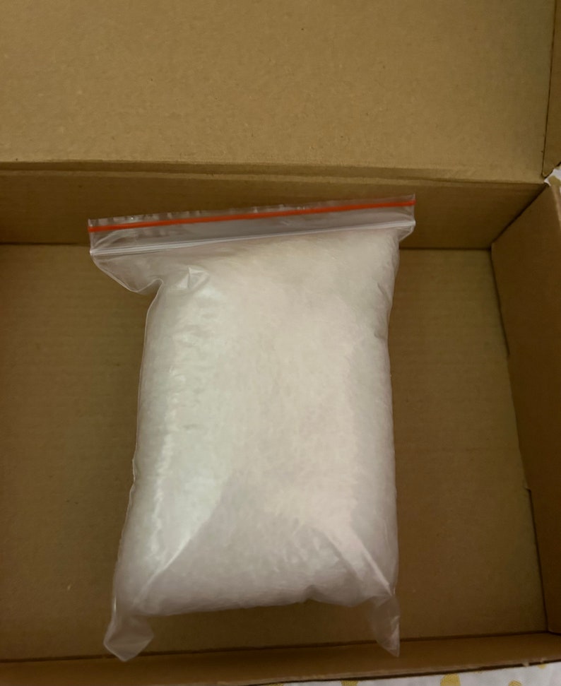 K&ouml;nnte beinhalten: Ein durchsichtiger Plastikbeutel gef&uuml;llt mit wei&szlig;en Verpackungschips. Der Beutel liegt in einem braunen Karton.