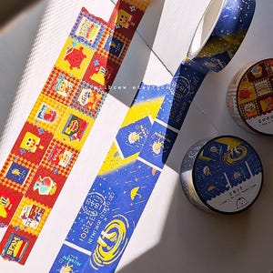 May include: Two rolls of decorative washi tape. One roll features a red and yellow checkered pattern with various food icons. The second roll is dark blue with yellow salt-themed graphics, text reading IODIZED 1848 NET WT 26 OZ, and stars.