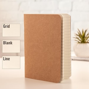 May include: A brown notebook with a kraft paper cover and a lined interior. The notebook is closed and sitting on a white surface.