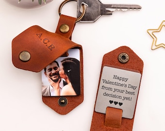 May include: A brown leather keychain with a photo insert and a metal tag that says "Happy Valentine's Day from your best decision yet!" with three hearts. The keychain has a key ring and a personalized inscription that says "A.C.R."