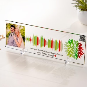 May include: A clear acrylic photo frame with a couple's photo, a colorful sound wave, and a green and red floral design. The frame has a stand and the text "Love you to infinity and beyond baby, your Panda always ❤️".