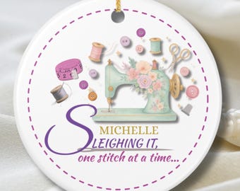 May include: A white, round ornament with a gold string for hanging. It features a watercolor illustration of a vintage sewing machine, spools of thread, buttons, and scissors. Text reads "MICHELLE LEIGHING IT, one stitch at a time..."