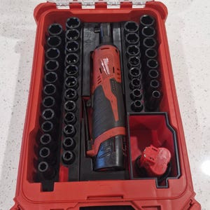 May include: A red and black Milwaukee tool set in a red plastic case. The set includes a power ratchet, sockets, and a battery. The case is open, revealing the tools neatly organized inside. The tools are black and silver.
