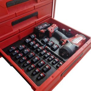 May include: A red Milwaukee Packout tool storage unit with an open drawer containing a black foam insert. The insert holds a red and black cordless impact wrench, a battery, and a collection of black metal impact sockets with white labels.