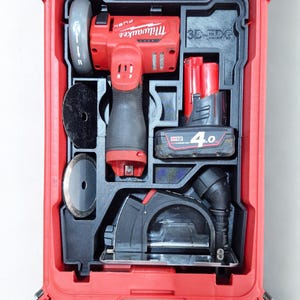 May include: A red Milwaukee power tool kit containing various tools and accessories. The kit includes a red and black angle grinder, a circular saw, batteries, and cutting discs. The tools are neatly arranged within a red carrying case.