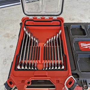May include: A red and black tool case with a clear lid, open to reveal a set of shiny, silver wrenches. The wrenches are neatly organized in a fitted interior. The case is part of a larger black tool storage system.