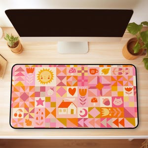 May include: Rectangular mousepad with a colorful geometric pattern in shades of pink, orange, and yellow. The design includes various icons such as a sun, house, heart, and flowers. The mousepad has a black border.
