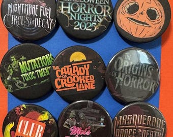 May include: Nine black round buttons with Halloween Horror Nights designs. The buttons feature text and graphics like a jack-o'-lantern, "Nightmare Fuel Circus of Decay," and "Halloween Horror Nights 2025." Other buttons include "Mutations Toxic Twent," and "Club Horror."