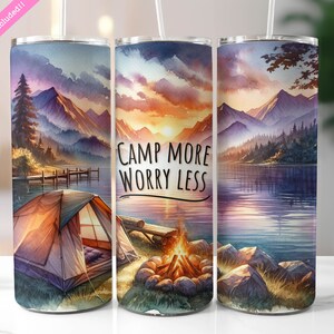 May include: Three stainless steel tumblers with a watercolor design of a lake, mountains, and a campsite. The middle tumbler has the text "Camp More Worry Less".