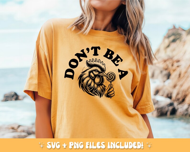 May include: Mustard yellow t-shirt with the text "DON'T BE A" above a detailed black and white illustration of a rooster holding a lollipop. The shirt includes SVG and PNG files.