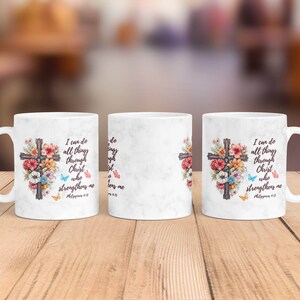 May include: White ceramic mug with a floral design and a cross. The mug has the text "I can do all things through Christ who strengthens me" and a Bible verse reference.