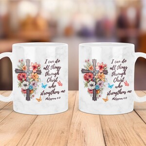 May include: White ceramic mug with a floral design and a cross. The mug has the text "I can do all things through Christ who strengthens me Philippians 4:13" printed on it.