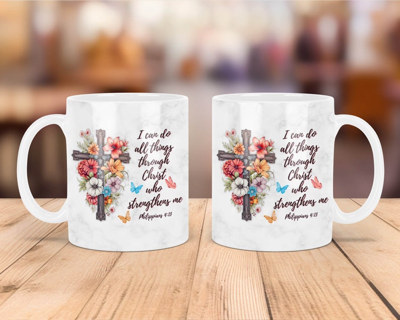 May include: White ceramic mug with a floral design and a cross. The mug has the text "I can do all things through Christ who strengthens me Philippians 4:13" printed on it.