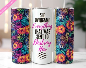 May include: A white tumbler with a tropical print featuring flowers, leaves, and leopard print. The text "She Overcame Everything That Was Sent To Destroy Her" is printed in black and pink on the tumbler.