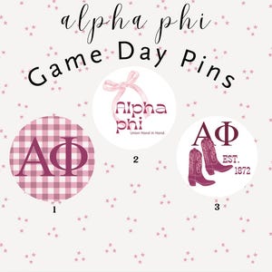 May include: Three round pins with the text "Alpha Phi Game Day Pins". The pins feature the Greek letters ΑΦ, a bow, and cowboy boots. The background is a light pink with small star shapes.