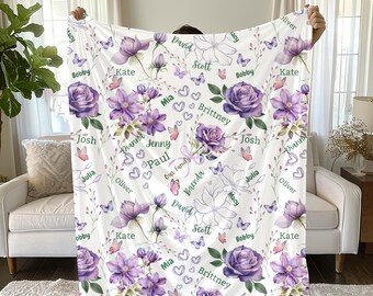 May include: White personalized blanket featuring purple floral and butterfly designs. Names are printed throughout the design. The blanket is held up by a person.