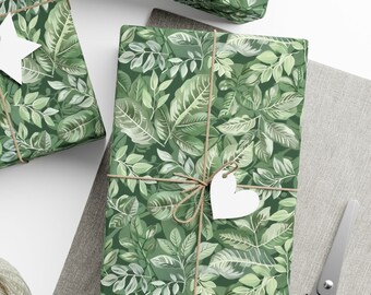 May include: Three green gift boxes with a leafy pattern are tied with twine and decorated with white paper stars and hearts. The boxes are on a white surface with a gray fabric background.