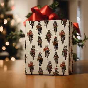 May include: White gift wrap with a repeating pattern of black cats riding motorcycles and wearing Santa hats. The cats are holding Christmas greenery and ornaments.