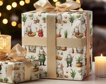 May include: Two gift boxes wrapped in white paper with a festive pattern of Santa Claus chefs cooking vegetables. The paper has a gold glitter finish. The boxes are tied with gold ribbon.