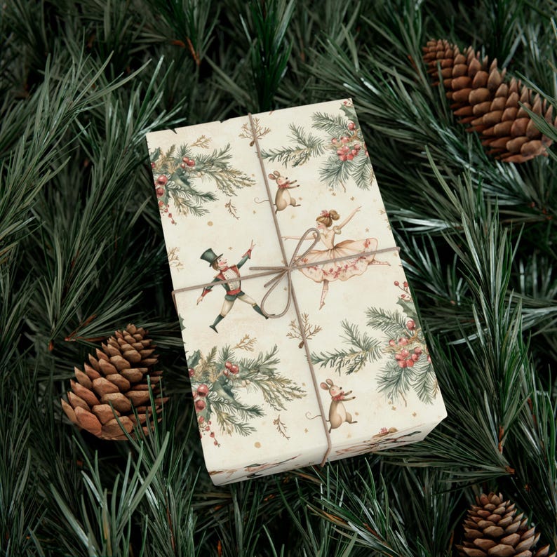 May include: A white gift wrap with a repeating pattern of a nutcracker, a ballerina, and mice. The pattern is surrounded by green pine branches and red berries.