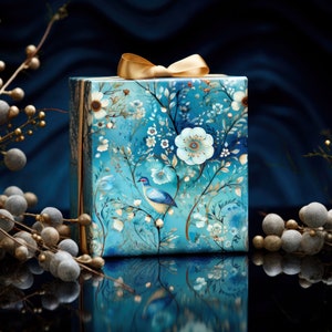 Pode incluir: Uma caixa de presente azul com uma fita dourada e um design floral. A caixa apresenta um pequeno p&aacute;ssaro azul em um galho.