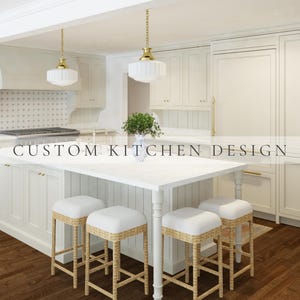 May include: A kitchen featuring white cabinetry, a central island with four stools, and two pendant lights. The stools have light-colored woven bases and white cushions. The text CUSTOM KITCHEN DESIGN is overlaid across the center of the image.