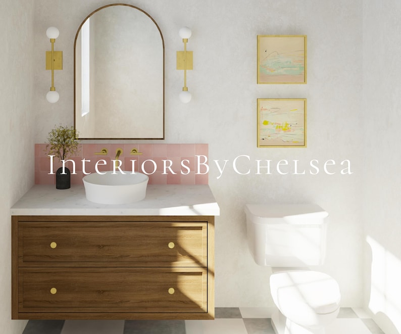 May include: A bathroom vanity with a wooden cabinet, two drawers with gold knobs, a white countertop, and a round vessel sink. Above, an arched mirror is flanked by two gold wall sconces. Pink tiles line the wall, and two framed art pieces hang nearby.