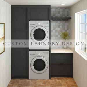 May include: A custom laundry design featuring a stacked white washer and dryer unit integrated into dark charcoal cabinetry. The setup includes a white countertop, a gray tiled backsplash, a black shelf, and a framed landscape print on the wall.