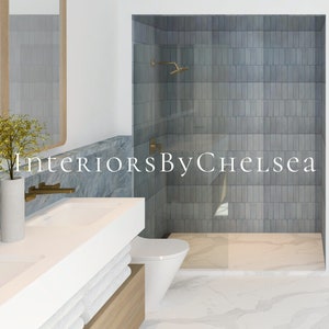 Puede incluir: Un baño moderno con un tocador de doble lavabo blanco, un inodoro blanco y una ducha a ras de suelo con azulejos de metro grises. La ducha tiene una puerta de vidrio y un cabezal de ducha dorado. El tocador tiene una base de madera y toallas blancas. El suelo es de mármol blanco. El texto "Interiors By Chelsea" es visible en la imagen.